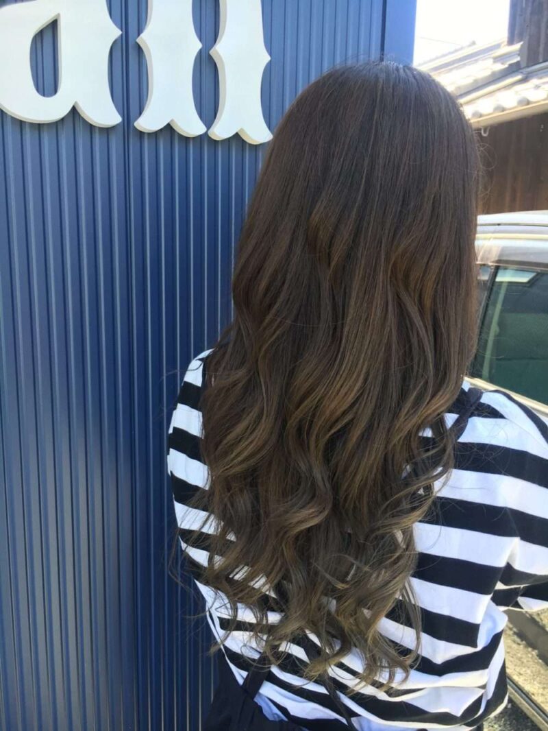 a woman with long hair in front of a blue wall