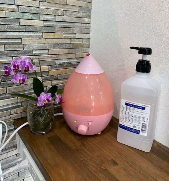 a pink and white air humidifier next to a bottle of liquid